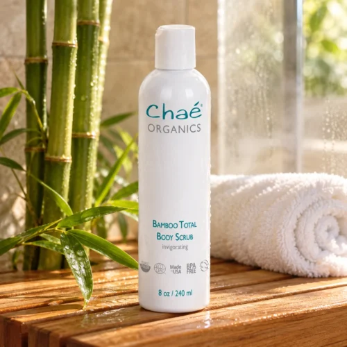 Chaé Bamboo Total Body Scrub (Mild Exfoliation) on a teak shower bench with bamboo and a rolled towel