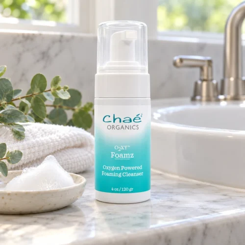Chaé Foamz (Oxygen Powered Cleanser) beside a bathroom sink with a dish of foam, a towel and eucalyptus