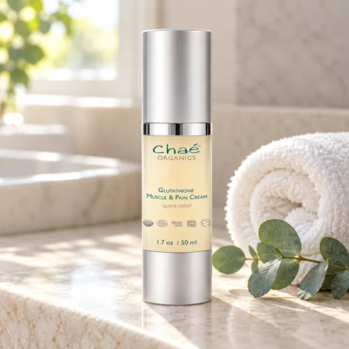 Chaé Glutathione (Muscle and Pain Cream) on a stone counter with a rolled towel and eucalyptus