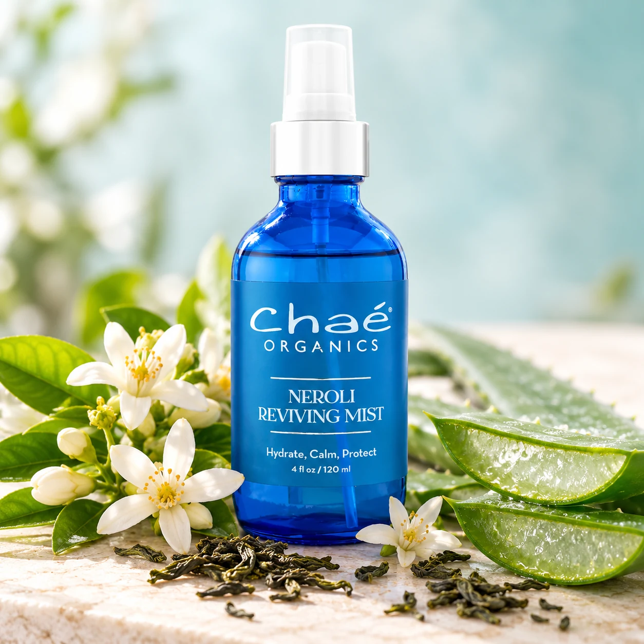 Neroli Reviving Mist with white orange blossoms, a few loose green tea leaves and a split fresh aloe vera leaf