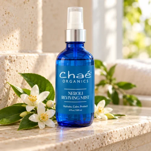Chaé Neroli Reviving Mist (Hydrate, Calm, Protect) on a stone shelf with orange blossoms