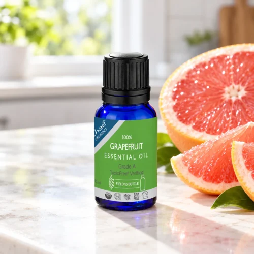 Chaé Grapefruit Essential Oil on a kitchen counter beside a halved pink grapefruit