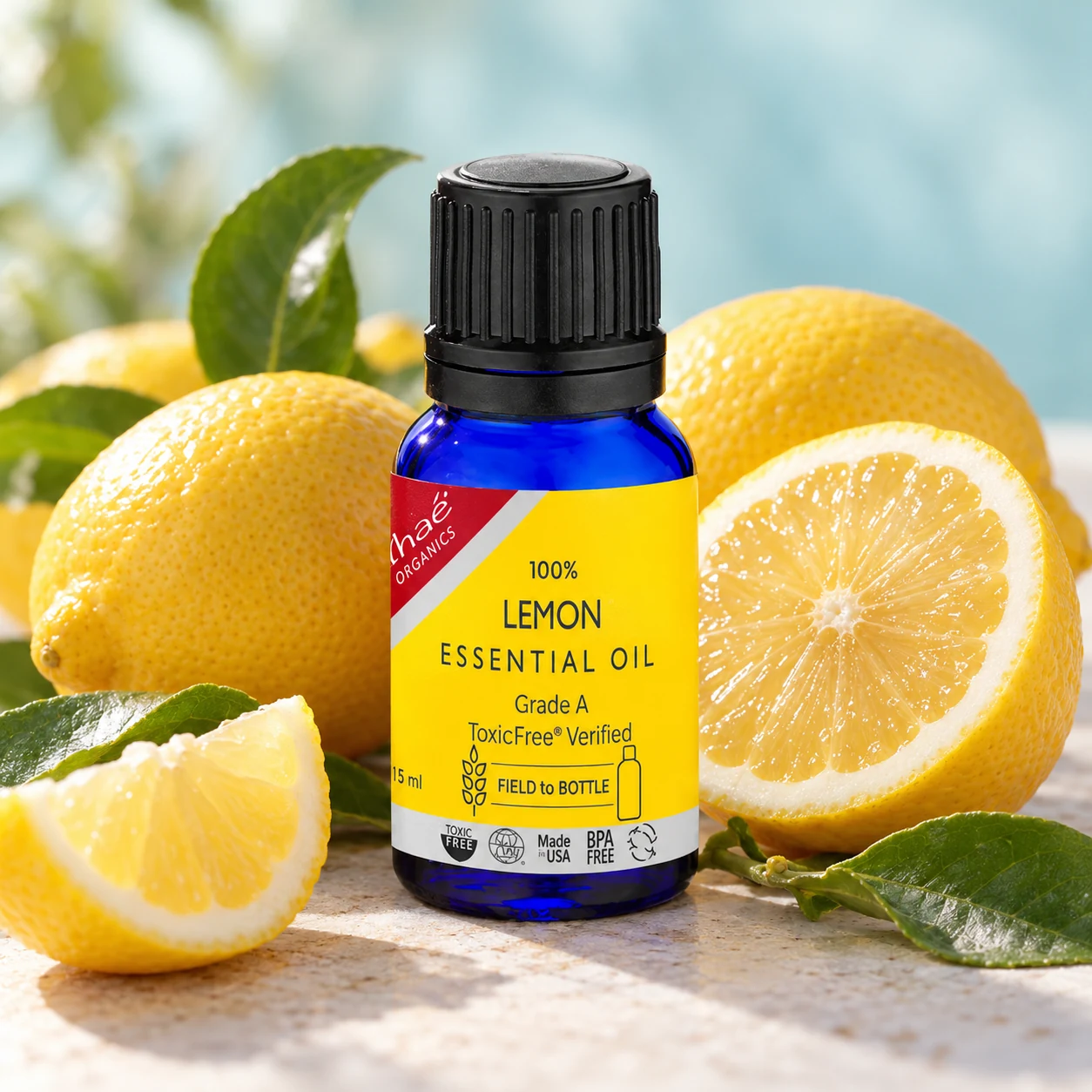 Lemon Essential Oil with fresh lemons, one of them halved, with a few lemon leaves