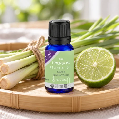 Chaé Lemongrass Essential Oil on a bamboo tray with fresh lemongrass and a halved lime
