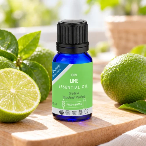 Chaé Lime Essential Oil on a wooden board beside fresh limes