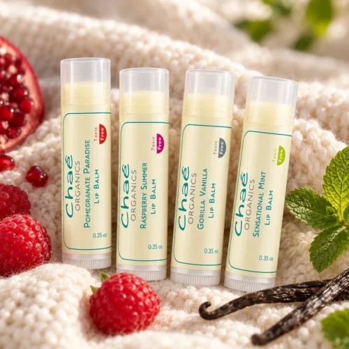 Chaé Lip Balm (Everyone’s Favorite!) in all four flavors on a knit blanket with raspberries, a vanilla pod and mint