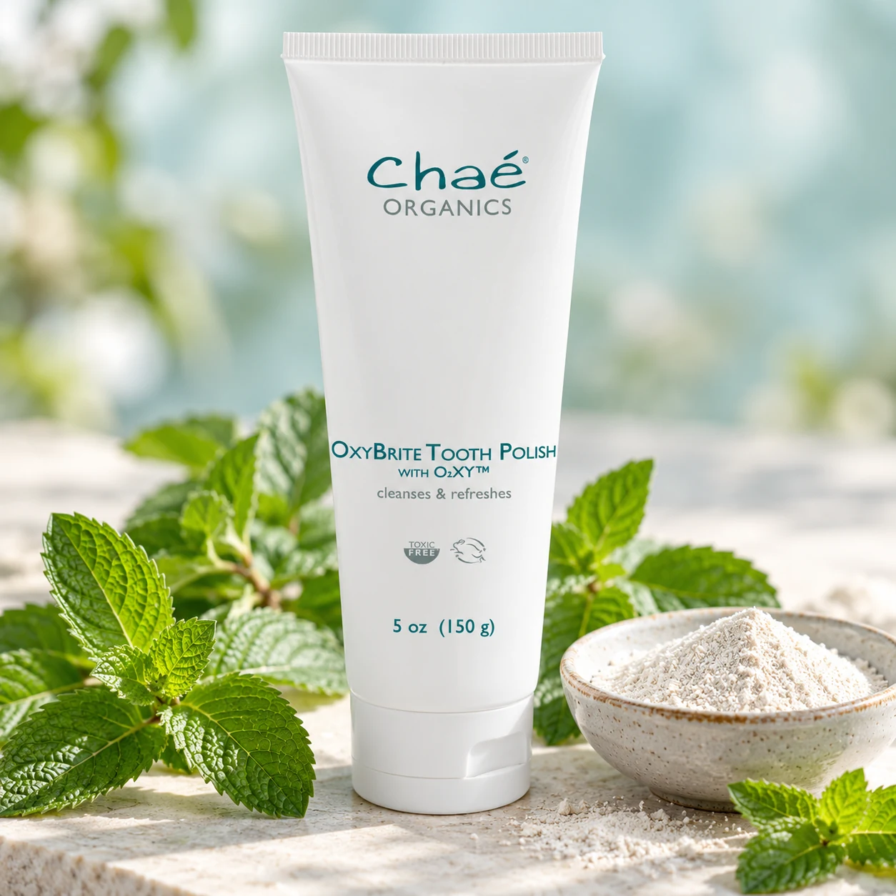 OxyBrite Tooth Polish with fresh peppermint leaves and a small dish of fine white mineral powder