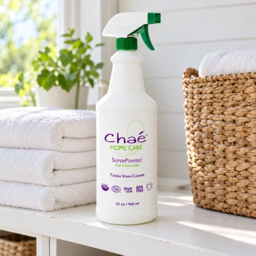 Chaé SuperPowerz (Tough Stain Cleaner) on a laundry-room shelf with folded towels and a seagrass basket
