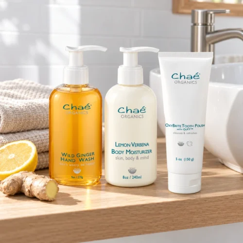 Chaé Head to Toe Kit — Wild Ginger Hand Wash, Lemon Verbena Body Moisturizer and OxyBrite Tooth Polish on a wood shelf by a bathroom sink