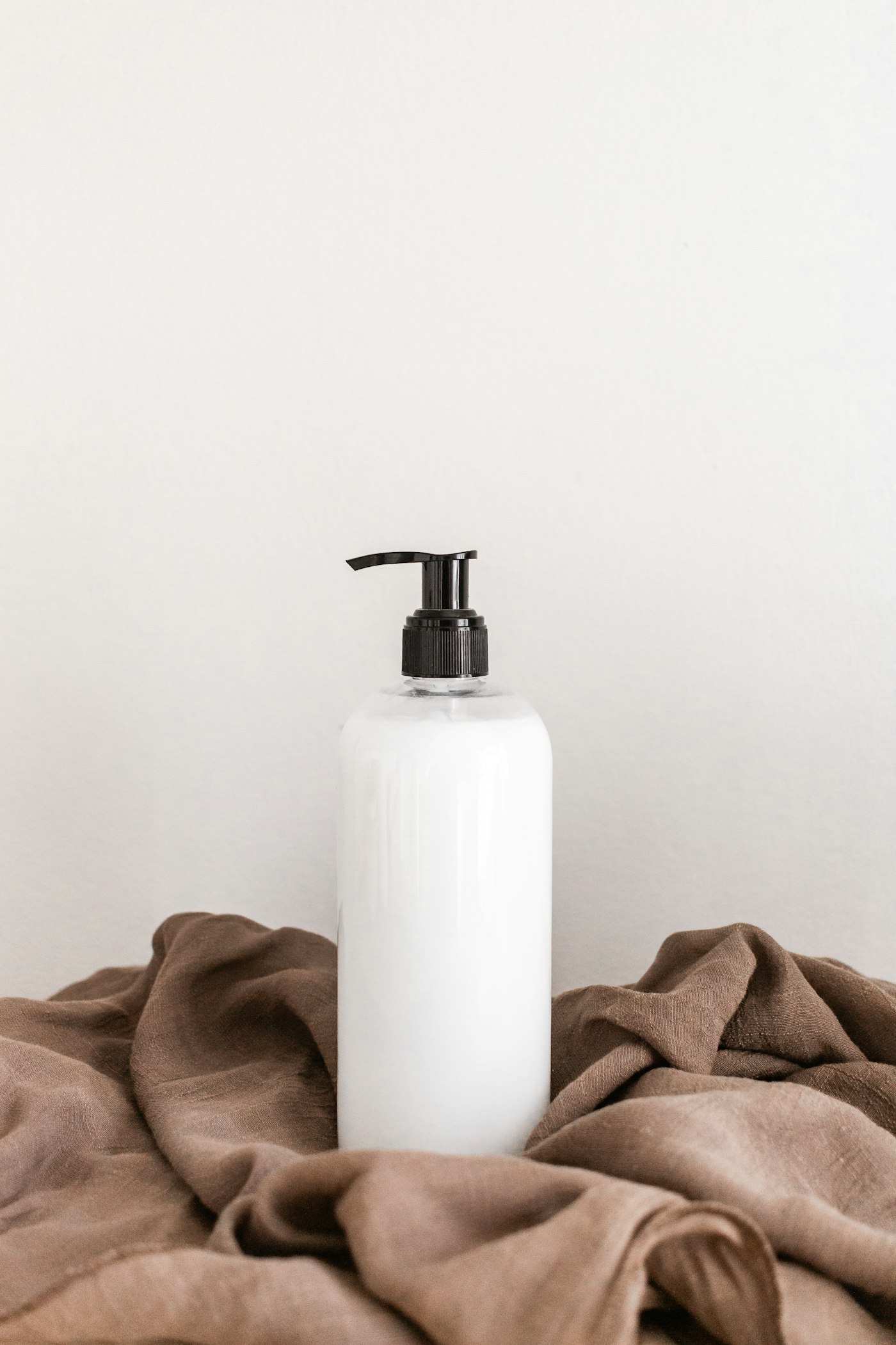 An unlabeled white pump bottle standing on a folded linen cloth